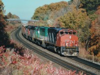 We're just to the east of Bayview, at a location now known as "Snake"; I guess in reference to the bridge in the background that leads to the Beth Jacob cemetery there. I am comfortably settled into a quiet spot along the hillside where I used to go when I wanted to say "the hell with the world".  That is partly what railfanning is all about, isn't it? I remembered taking this late afternoon picture when, the other day, I was viewing a video shot by the late Lloyd Hodges of down Niagara-area; someone I did not know at the time, when I saw that he filmed this at Burlington West, I thought "hey, I saw this train as well". And sure enough, that afternoon here I was some 3 miles west down the line. On a clear day one could see...............but on this slightly hazy afternnon in the far background best I can make out is Waterdown Rd bridge and the former Aldershot Cold Storage building, a white dot, on the right. Power on this train is CN 9408, 9668, 9308 and 9305, with 129 cars in tow. All units off the roster now......the 9668 came to CN in from GO Transit in a group of 10, it was the former GO 700, nee 9808.