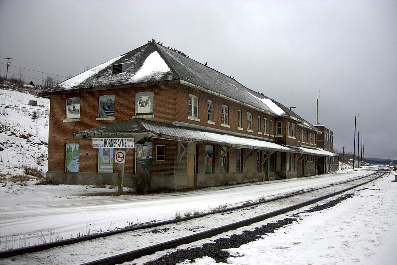 Further to Mr. Mooney's August 9, 1985 photo from the backside of CN's Hornepayne station, here is what it looked liked from the front side 16 years later in December 2001.  The absence of tenants, heat and caretakers has certainly taken its toll on the once busy structure. I am sure that in 2015, 14 years after this shot, the station and attached buildings must be a total disaster. The shop building (behind me) was still active in 2001 when I was there commissioning a new snow fighting machine. It stored CN vehicles, some work equipment machines, and a few pieces of rolling stock required for emergency purposes, and, the under roof turntable was still functioning. The town, the station, the shops and yard are but a shadow of themselves from when I lived and worked there in the 60's, 70's and 80's. Hornepayne has become but another casualty of the bigger, better, stronger, faster, more reliable trains, track, and service personnel across the system. Although that is a sad commentary, it is a good thing for railroading.
