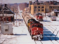 The GEXR takeover of the Guelph Sub was in its' infancy at 5 months when this shot was taken; and the railroad was forced to lease CN locomotives in order to cover all bases. Here we see from the Margaret Av overpass the eastbound morning GEXR #432 as it passes the Kitchener VIA station. Power is a couple of leased CNs, 9661 and 9633 with GEXR 4046 trailing. The CNs have long since departed the roster, and the GEXR has been scrapped. The area in this photograph is undergoing massive changes as preparations for GO service is under way.