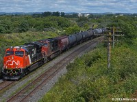 Barely dodging a spoiler cloud, CN 3001 lead IC 2719 and CN 3000 as DPU on 305's train at Bowmanville. I'm not sure exactly how these clouds know exactly where they are not wanted, but they seem really good at appearing at the wrong time. I'm not talking an errant drifter either, no, the sky above was clear (unlike in the background). This bugger formed spontaneously as the train approached. Oh well, almost CF'ed me, but not quite.
<br><br>
Their progress is already waning as YQ has instructed them to hold off getting to Oshawa East as there is a traffic jam in the 'Shwa' due to a dead unit on 306. It cost them about an hour, which is likely not welcomed by a crew that started it's day in Montreal. 1341hrs.