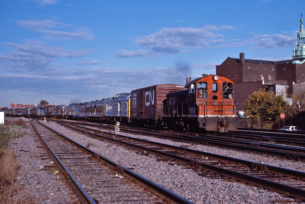 CN 7395 leads a transfer through St. Henri with a mixture of VIA equipment and two CN box cars.  The VIA equipment includes RDCs, Steam Generators and baggage cars, sporting CN, CP and VIA schemes.