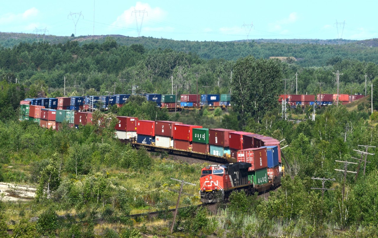 ES44DC 2327 shoves Vancouver bound train 101 up the hill through Coniston. Over 13500 feet of traffic lead by CN 8019, middle DP CN 2682 and tail end remote CN 2327.