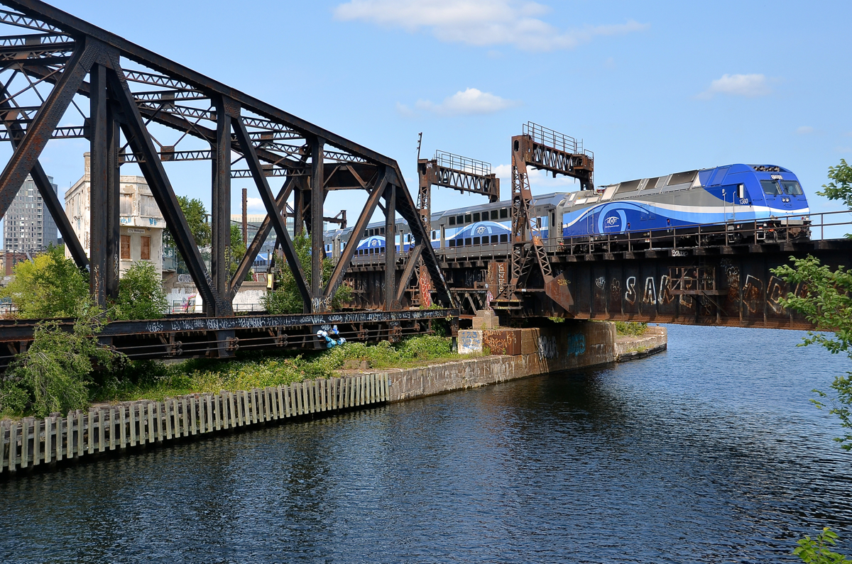 Swing bridge locked in place, lift bridge no longer lifts. AMT 1360 is pushing AMT 811 over what was once a lift bridge and beside a swing bridge that is locked in place along the Lachine canal.