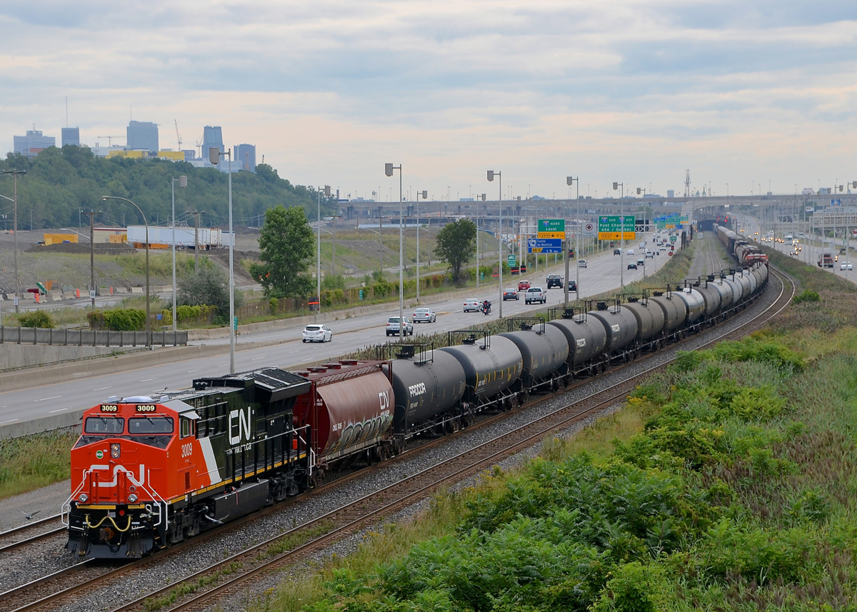 Fresh power leading CN 305. Delivered to CN only about a week ago, CN 3009 is in charge of CN 305 as it approaches a crew change at Turcot West. Older GEVO CN 2934 is mid-train. The skyline of downtown Montreal is visible at left.