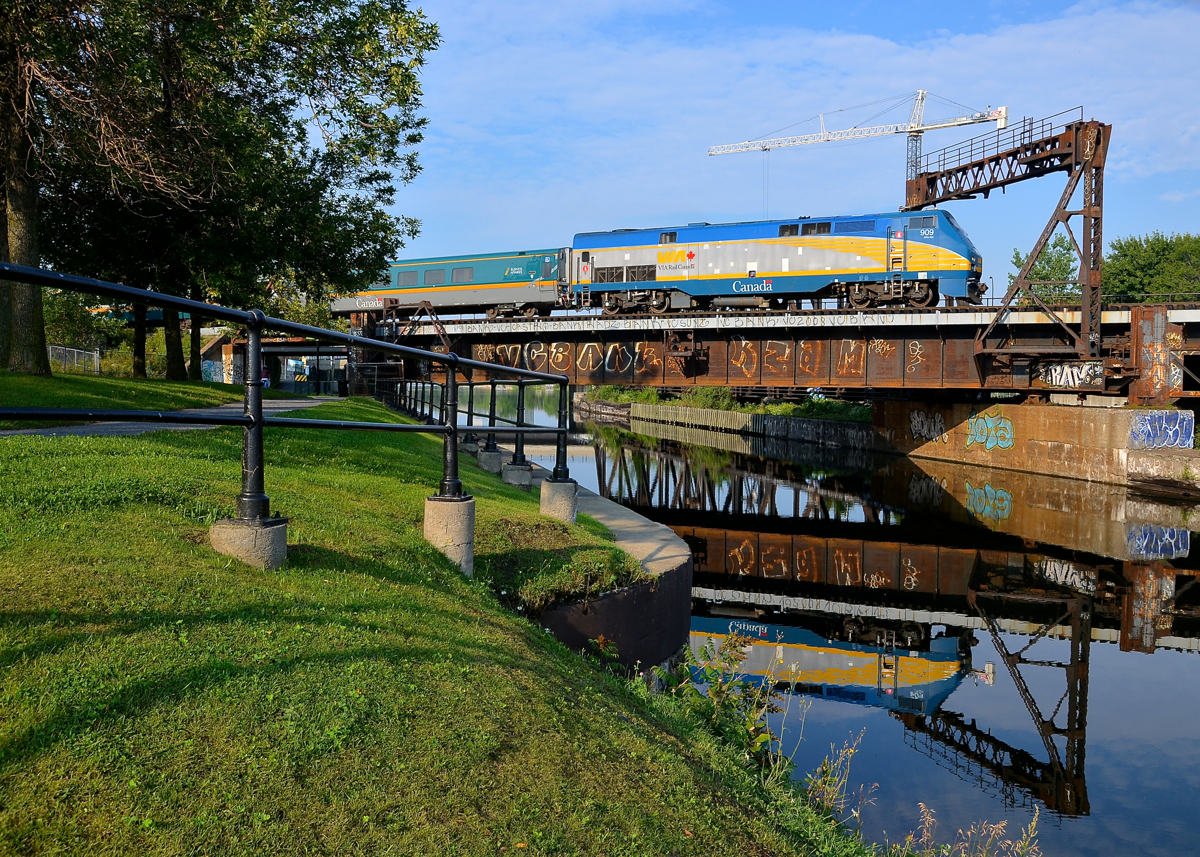 VIA 909 reflected in the canal. VIA 909 leads a slightly late VIA 33 from Quebec City over the Lachine Canal. After loading passengers at Montreal's Central Station, the train will back up and head to Ottawa.