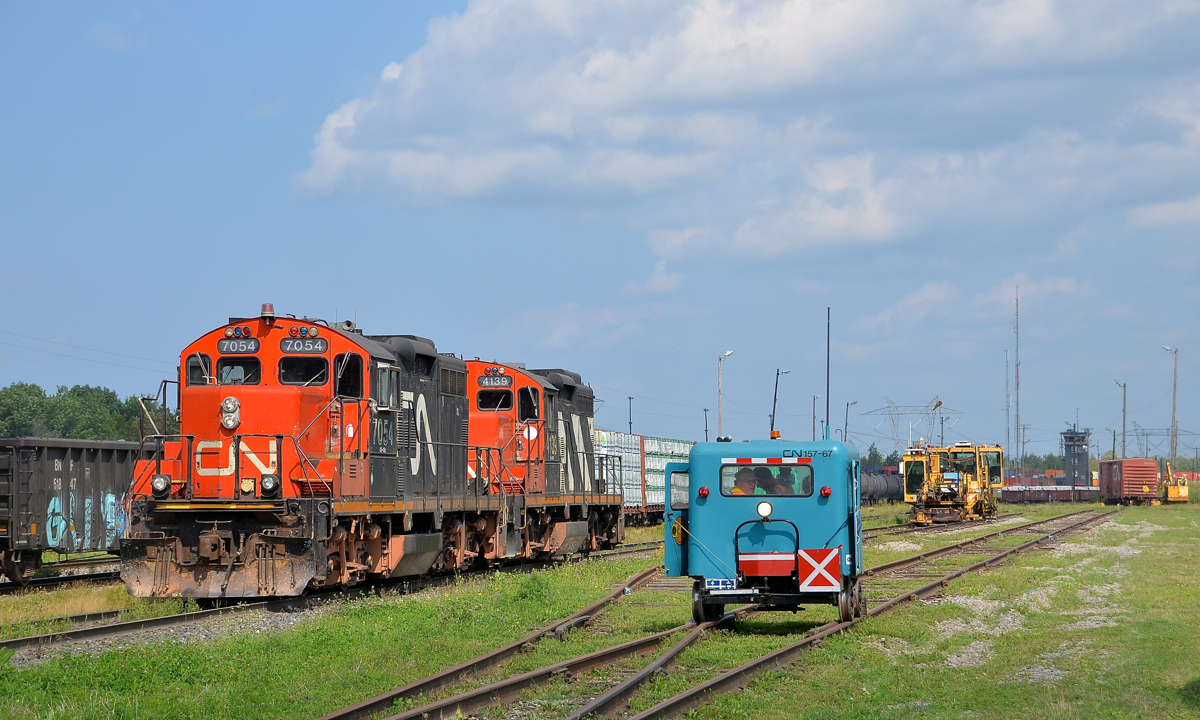 Beltpack demonstration. GP9's CN 7054 & CN 4139 are taking part in beltpack demonstrations available to those who attended CN family day at Joffre yard today. Another activity going on was speeder rides, with one at right. At left CN 309 doubles its train.