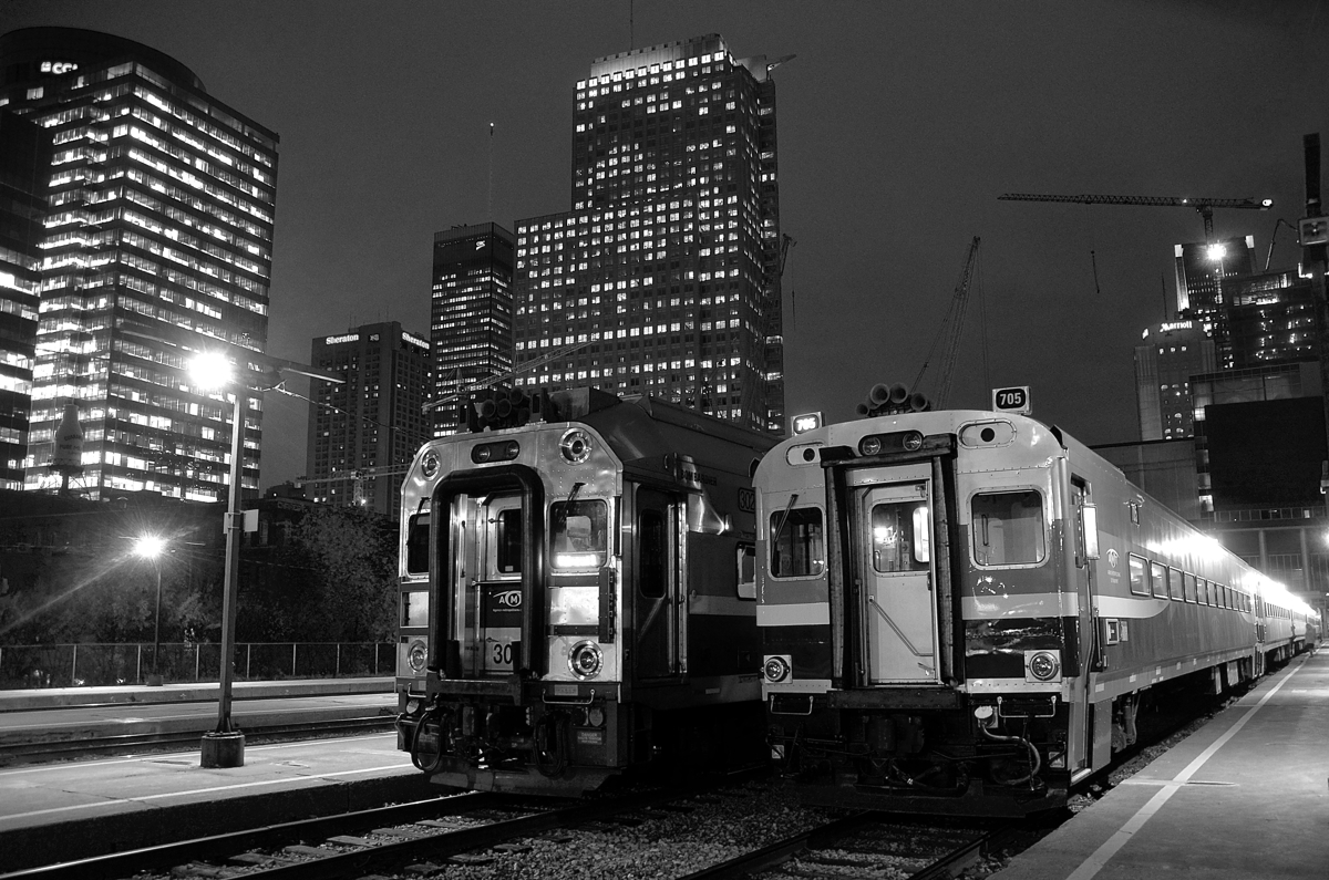 At Lucien L'Allier Station in Montreal, two of the last commuter trains of the rush hour are boarding passengers before heading west. At right is AMT 95, the 6:20 PM departure for Candiac and to its left is AMT 29, the 6:30 PM departure for Vaudreuil. At right is the Bell Centre, home of the Montreal Canadiens.