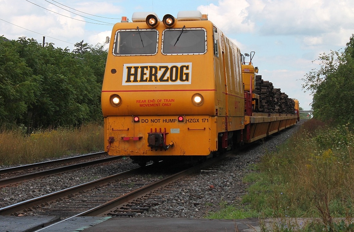 Herzog unit on the south track coming down Woodstock bank and crossing Norwich Avenue foot crossing. The train had a load of old wooden sleepers.