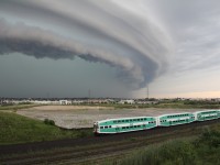 A WB GO train  passes an approaching summers afternoon thunderstorms au minus clouds.   