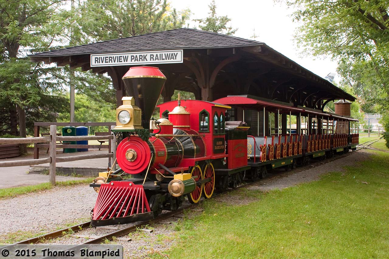 As part of its commitment to the city, the Peterborough Utilities Commission operates the Riverview Park Zoo, including the ever-popular miniature railway, which uses a gasoline-powered locomotive to pull the train across the Otonabee River on a short loop of narrow-gauge track. The train is seen at the Riverview Park station before the first trip of the morning.