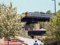 Pedestrians go by their daily activities on the downtown trail below, as the lead Budd RDC-1 on VIA #663 pops into view on the bridge above the Speed River as it arrives in Guelph.