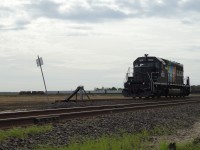 Canadian Wheat Board (CWB) SD40-2 number 1002 sits at the brand-new loop-track CWB Grain Elevator located west of Bloom, Manitoba. In the background, an eastbound CN manifest freight, led by CN 2615 (C44-9W) and CN 8906 (SD70M-2), speeds past the elevator on the nearby Rivers Sub. 