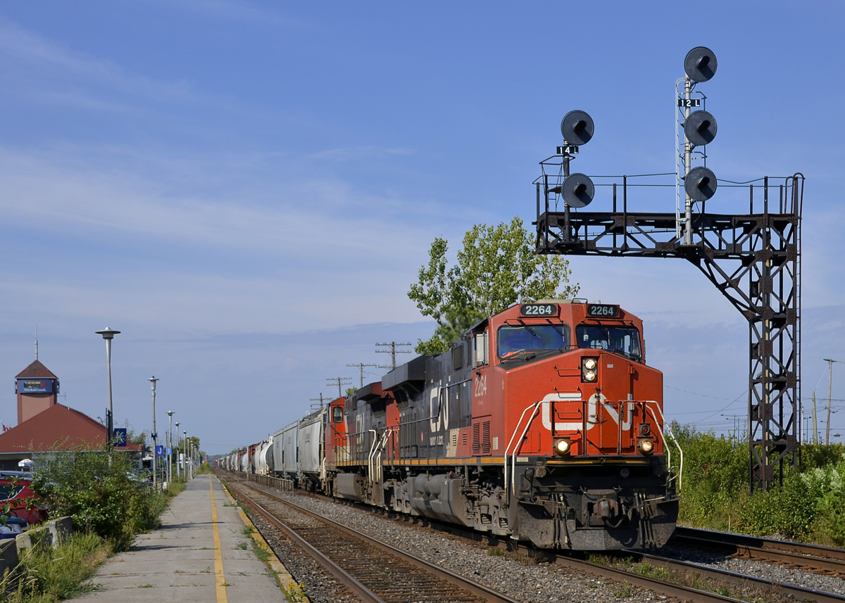 GEVO and Dash9 leading. CN 2264 & CN 2686 lead CN 368 past VIA's Dorval station on a warm and sunny morning.