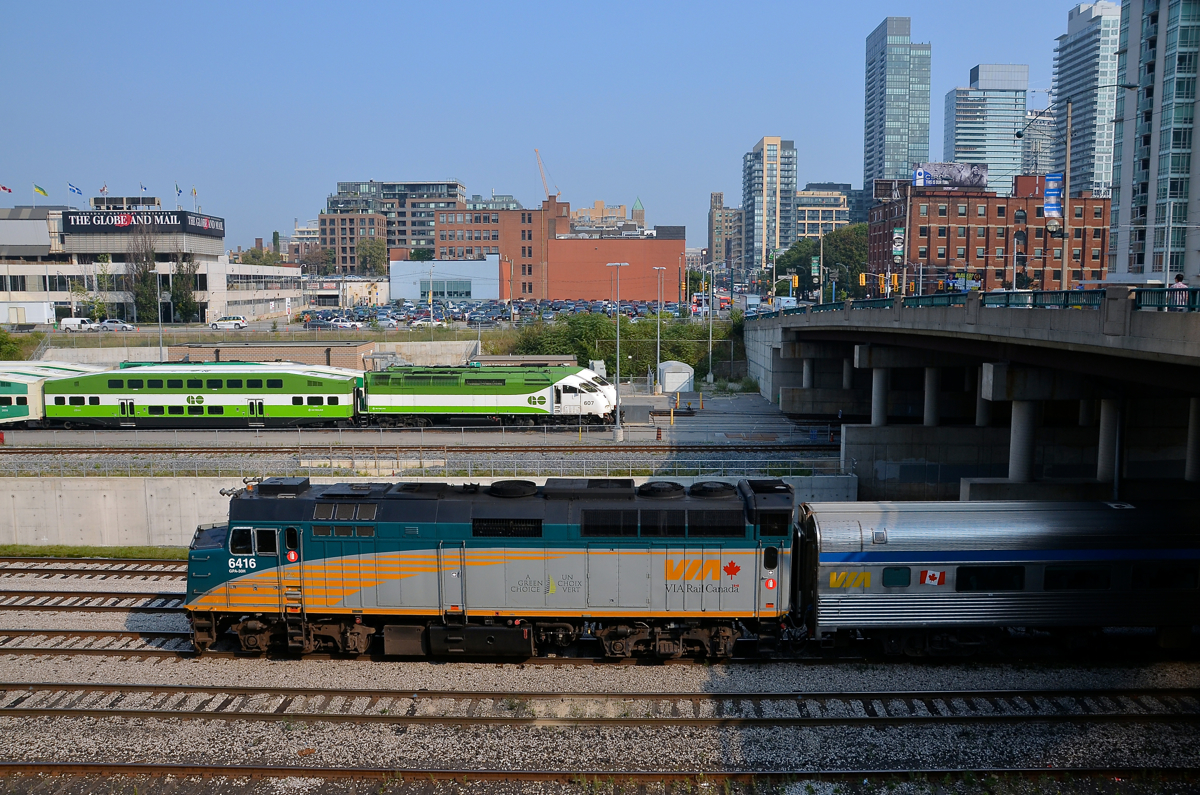 VIA & GO Transit west of Union Station. VIA 6416 backs a deadhead movement east towards Union Station in Toronto. In the distance are a number of trains laying over in the GO North Bathurst Yard.