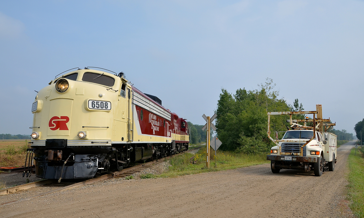 Ontario Southland Railway, on the rails and on the road. Freshly repainted FP9A OSRX 6508 is leading GP9 OSRX 1620 as they head light to pick up some cars at Putnam. Waiting at the crossing is an Ontario Southland Railway hi-railer.