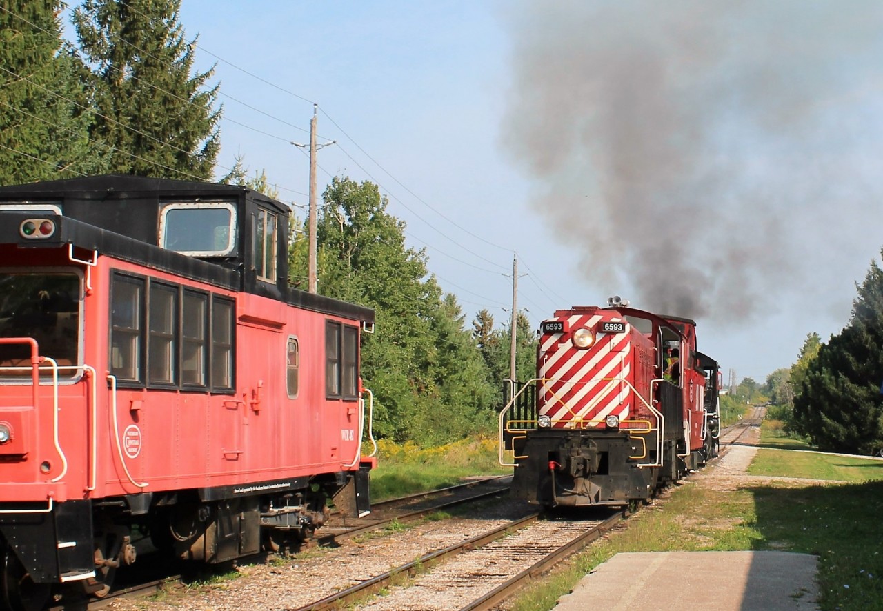 Former CP 6593 (MLW S3) now owned by the Waterloo Central Railway, pushes Essex Terminal Railway Steam Locomotive #9 away from the station and out over the Conestogo River bridge, and away from the neighbouring houses, so the steamer can switch from a wood fired operation to coal fired for its afternoon holiday Monday run. Both show a nice plume. WCR caboose 482 will be lashed to the end of the train.