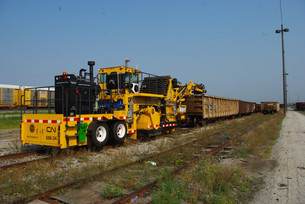 Not everything that moves railcars is from GM or GE. With operator orientation, air brake and car coupling/movement training complete, CN 686-34 a brand new Knox Kershaw KYC550 yard cleaner is ready to start work.  We have just coupled to gondola WC 54226 and will move it over one track in order to get at CN 188314 which will be an assigned car for the new machine. Over time, cargo shakings from a variety of shipments such as grain, plastic pellets, potash, and other commodities sift from cars and collect in the yard tracks. After a pass with the KYC550 these tracks they will be clean right down to the wood.