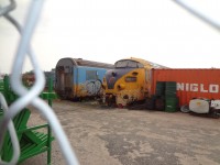 In August 2002 I captured the retired ONR Tee Train on the deadline in ONR's North Bay yard. http://www.railpictures.ca/?attachment_id=5700#sthash.cvqIL53y.dpuf 
I have managed to get a shot of these remaining cars every few years since.  On a business trip to ONR this month, I once again came across the last remaining cars from the Tee Train set.
15 years later, one power car and one coach are unceremoniously dumped on the ground in a fenced compound at the end of a public parking lot off Oak Street in downtown North Bay. This trainset has clearly gone from bad to worse over the years. I wonder what, if anything I will find on my next trip.


