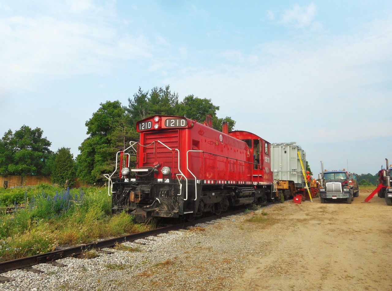 After getting word of transformers being moved for Hydro One the previous day, I headed down to Arkell to see what was going on. Finding OSR SW1200RSu 1210 sitting with two depressed center flats, one already unloaded (one transformer just behind me). Today's job was to unload the second transformer. Two small conveyor belts were placed under the transformer and on the flatbed truck. Slowly the load was shifted from rail-to-road, and the job was done. I noticed the flatcar behind the unit had an old clearance card on it from the Illinois Central Railway,meaning this card was approximately 20+ years old. To see the card click here: http://www.railpictures.ca/?attachment_id=19705