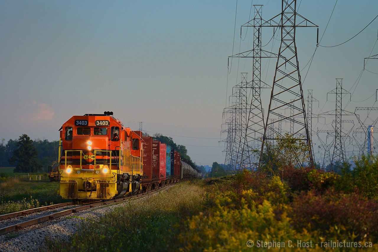 A beach day for me and my family - twice a year I visit Port Dover, and twice a year I have a chance of some SOR action down by Nanticoke - I don't always get lucky, but this was my lucky break as 4057 finally dissapeared from the Nanticoke job leaving just GW Orange. However, it's all in the timing - by the time I get everyone fed and  skin sufficiently tanned, where will 595 end up? I found them out on the road, which is awfully lucky, usually they are parked at the yard by this time
In this scene, 595 is heading TT west (north) on the rolling profile of the Hagersville sub, in the background are the codeline and a smokestack from the now idled Nanticoke Genrating Station, and the farmers fields of Haldimand county, all of which is lit by the last rays of the hot summer sun sometime after 7 PM.
As the train went by, the hogger gave us an extra toot of the horn - to the delight of my 5 year old. She put me up to this photo by asking me if we could  "see it again" after running into them the first time on the way home. She was delighted, as was I to oblige - with tummys full of beach food, our next destination was Hewwitt's dairy for for a malted milkshake, vanilla. A great day indeed. Thanks to the SOR crew for the extra toots of the horn and for making a little girl (and her boyish adult father) happy :)