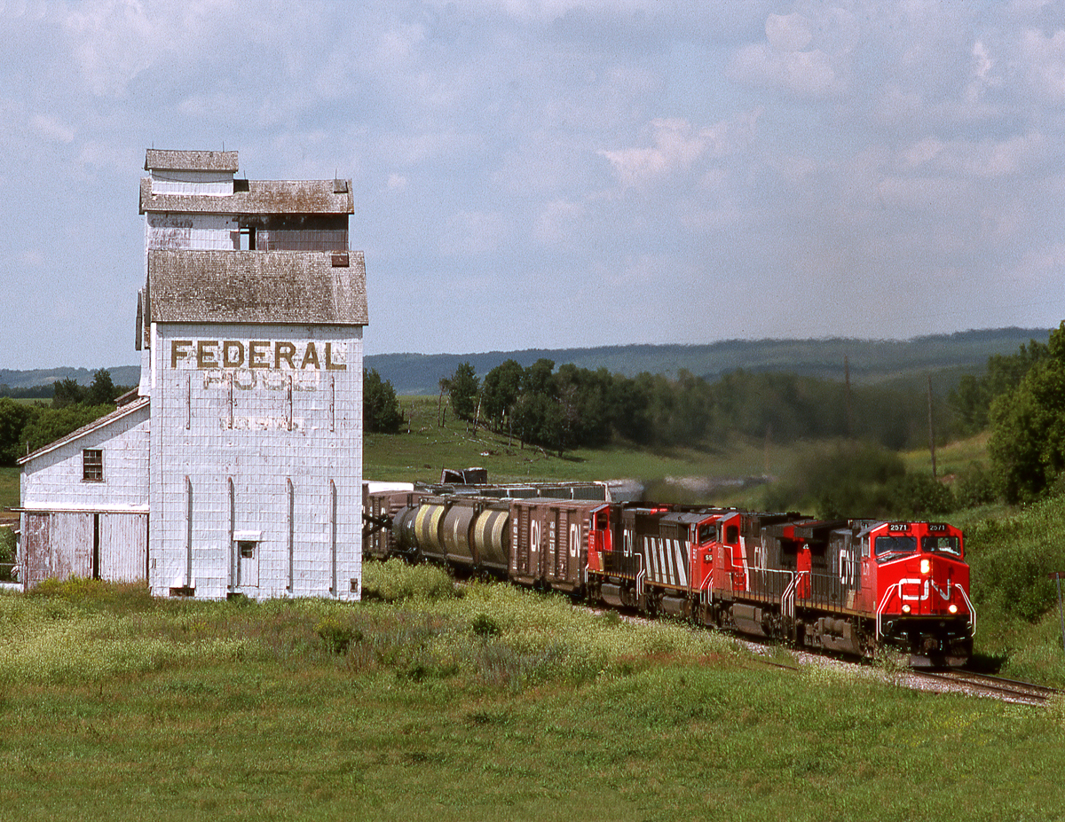 Eastbound CN freight 452 passes the derelict elevator at Runnymede as it climbs out of the Assiniboine Valley east of Kamsack on the Prairie North Line.