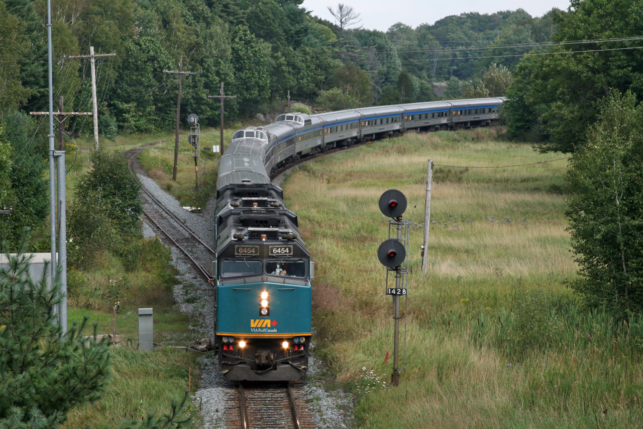 Having learned that VIA No.1 would be departing Toronto at 0900 (it's old departure time), due to the late arrival of VIA No.2 the previous evening; I wanted to try and recreate a shot of No.1 at Falding from 2007.
http://www.railpictures.ca/?attachment_id=803

Alot has changed in the 8 years between these photos. VIA has rebuilt their fleet of F40's, making the bright yellow and grey units a thing of the past.  The schedule for No.1 and No.2 has been drastically changed, with time added in an attempt to increase on time performance, resulting in a 2200 departure from Toronto.  It takes 8 hours to turn the train and when they arrive 10+ hours late, we get a rare daylight treat like this.  

Things have changed on the CN side as well.  The 6120' passing track at Falding is now a stub ended storage track, with the south switch being ripped out about a year ago.  Signal 1428 now protects a glorified location for Foreman and work trains to clear; maybe the odd hot box set out if required.  Due to the short length of the siding (6250feet is considered siding length) and being located on a 0.3% - 0.8% southward grade the siding was rarely used, except by well powered and short trains.  Not to mention, the siding was located 4 miles from the "double track" provided by the Directional Running Zone with CP and given the gradient, it was a risky meet location.  

While much has changed, some things have remained the same.  The classic shot from the overpass at Rankin Lake Road still provides a clear view of a northbound sweeping through the curve, with the old siding track swinging eastwards around some rocks and a pond.  The old searchlight signal remains, warning of approaching trains and protecting the old siding track.  Last, but not least, it is still impressive to watch VIA's the Canadian streak through Muskoka with 25 gleaming stainless steel coaches, diners, sleepers and domes as the engineer provides a friendly wave.