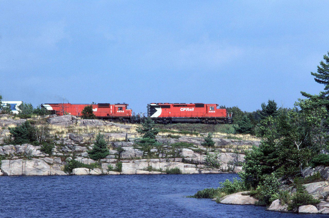 This eatbound CP intermodal train is traversing an outcrop that separates a couple laje in Grundy Provincial Park.