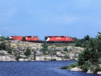 This eatbound CP intermodal train is traversing an outcrop that separates a couple laje in Grundy Provincial Park.
