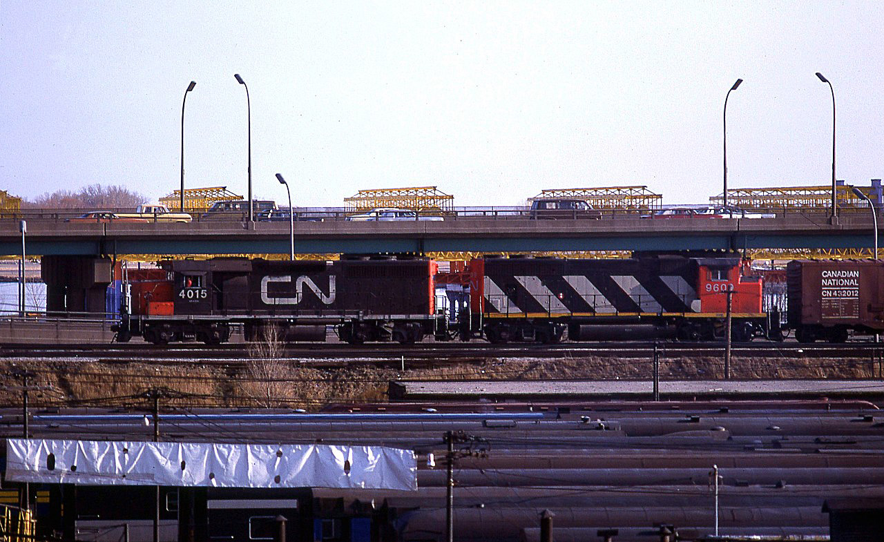 If Dave Brook is correct, this may be the "KO27 Mac Yard – Mimico transfer". It is on the somewhat elevated Union Station bypass tracks. In the foreground, the roofs of many passenger cars may be seen, resting in the Spadina Coach yard.
Above is the busy elevated QEW.