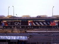 If Dave Brook is correct, this may be the "KO27 Mac Yard – Mimico transfer". It is on the somewhat elevated Union Station bypass tracks. In the foreground, the roofs of many passenger cars may be seen, resting in the Spadina Coach yard.
Above is the busy elevated QEW.