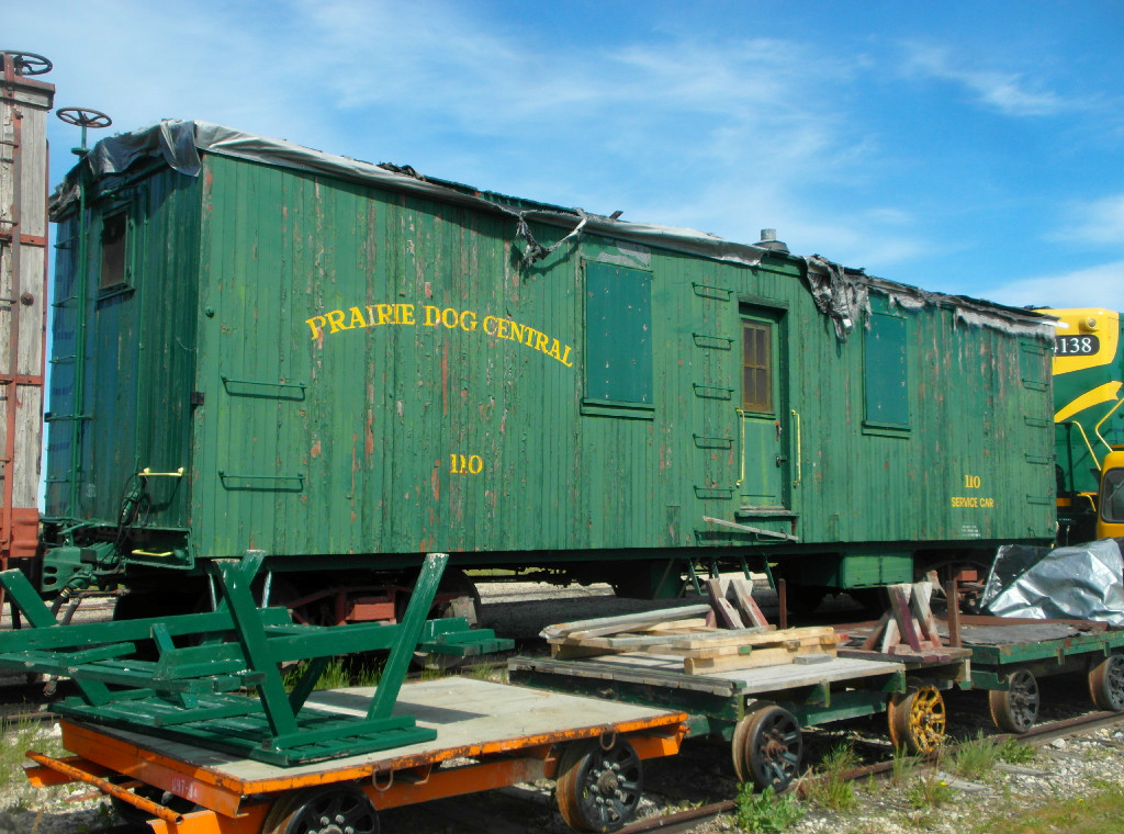 A very old boxcar/service car sits at the Prairie Dog Central yard. This wooden boxcar is slowly falling apart, with the paint coming off, and roof presumably collapsed.