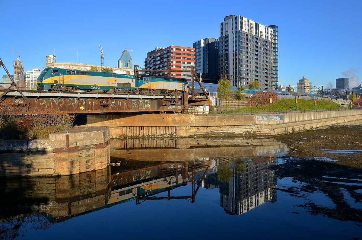 GE and EMD power past a mostly empty Peel Basin.VIA 903 and VIA 6401 are teaming up to push VIA 63 towards Montreal's Central Station on a crystal clear fall morning. In the foreground is the mostly empty Peel Basin, as the Lachine Canal and the Peel Basin are partially drained every fall.