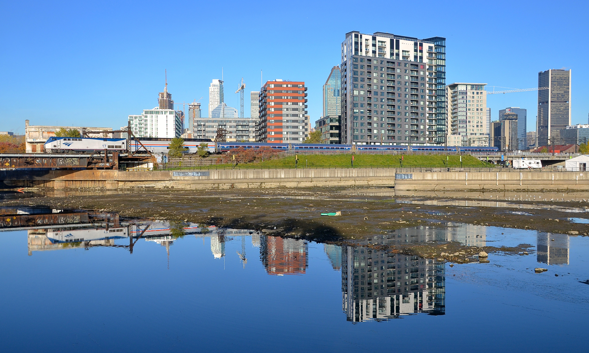 Missing some water for a full reflection. AMTK 17 pushes the Adirondack consist to Central Station, with great dome car 'Ocean View' at the head end. In the foreground is the mostly empty Peel Basin, as the Lachine Canal and the Peel Basin are partially drained every fall.