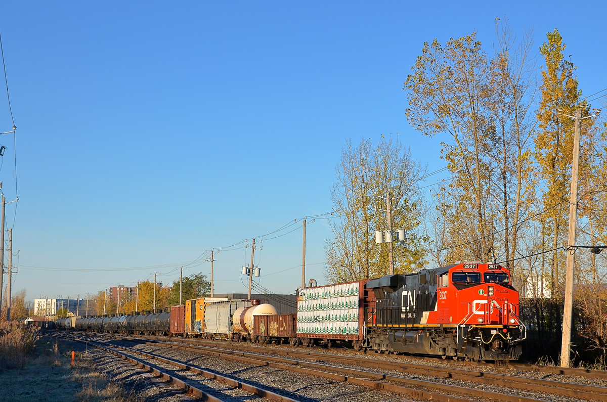 A fresh ES44AC on a sunny morning. On a cloudless morning CN 310 with clean CN 2937 at the head end is approaching Southwark Yard where it will do a setoff before continuing to Joffre Yard with a new crew. Operating mid-train is CN 2901.