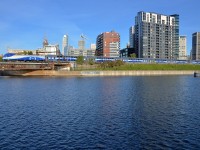 <b>A blue striped train.</b> AMT 809 passes the Peel basin before entering Central Station in Montreal. The blue stripes on the AMT train contrast with the darker blue water in the basin.