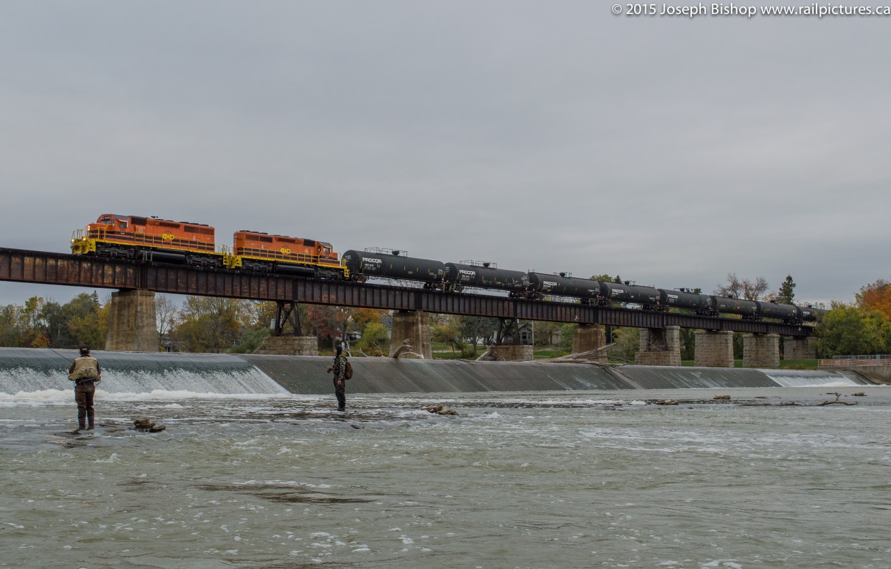 Gone Fishin'  As a pair of fishermen look on as RLHH 595 slowly crosses the Grand River in Caledonia with RLHH 3403, RLHH 3404 and 15 tank cars.