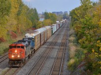 <b>A striped plow on a zebra striped cowl.</b> CN 5552, still sporting its striped plow as delivered, leads CN 401 towards nearby Taschereau yard. Trailing is 'blue devil' IC 2455.