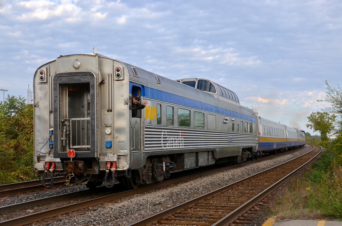 A VIA employee waves from the rear of 'Skyline' car VIA 8501 at it leaves Dorval after discharging its load of Rapido Train charter passengers.