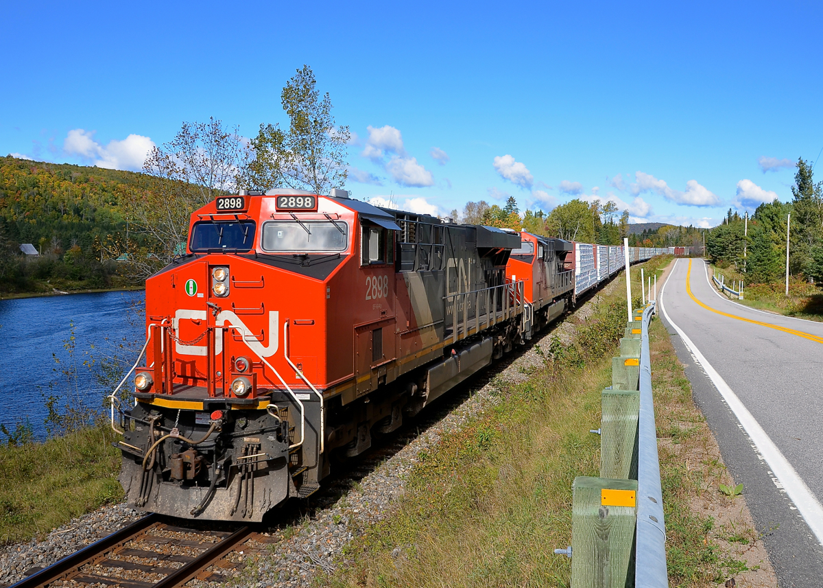 Between the river and the road. CN 369 is boxed in by the Batiscan river at left and Route 367 at right as it heads towards Garneau Yard in nothern Quebec. Power is 4 AC units: CN 2898 & CN 2949, along with CN 2854 & CN 3000 mid-train.