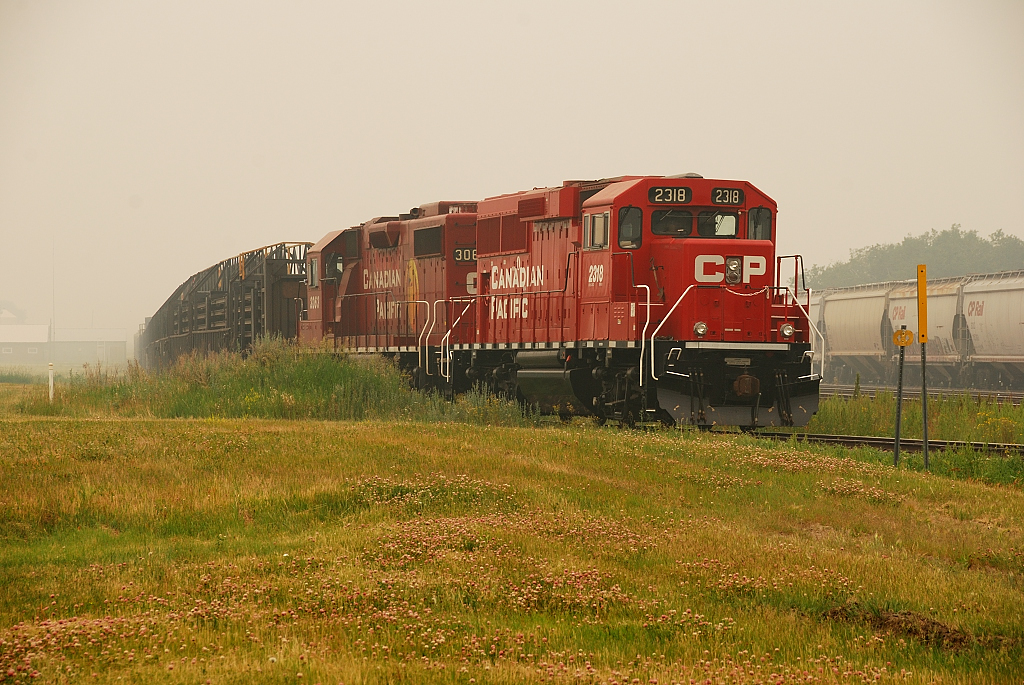 Forest Fire smoke blankets the area as a CP CWR train awaits a crew. The rail on this train was pulled up off the Gravelbourg Sub and will be used on CP's Tisdale Sub.