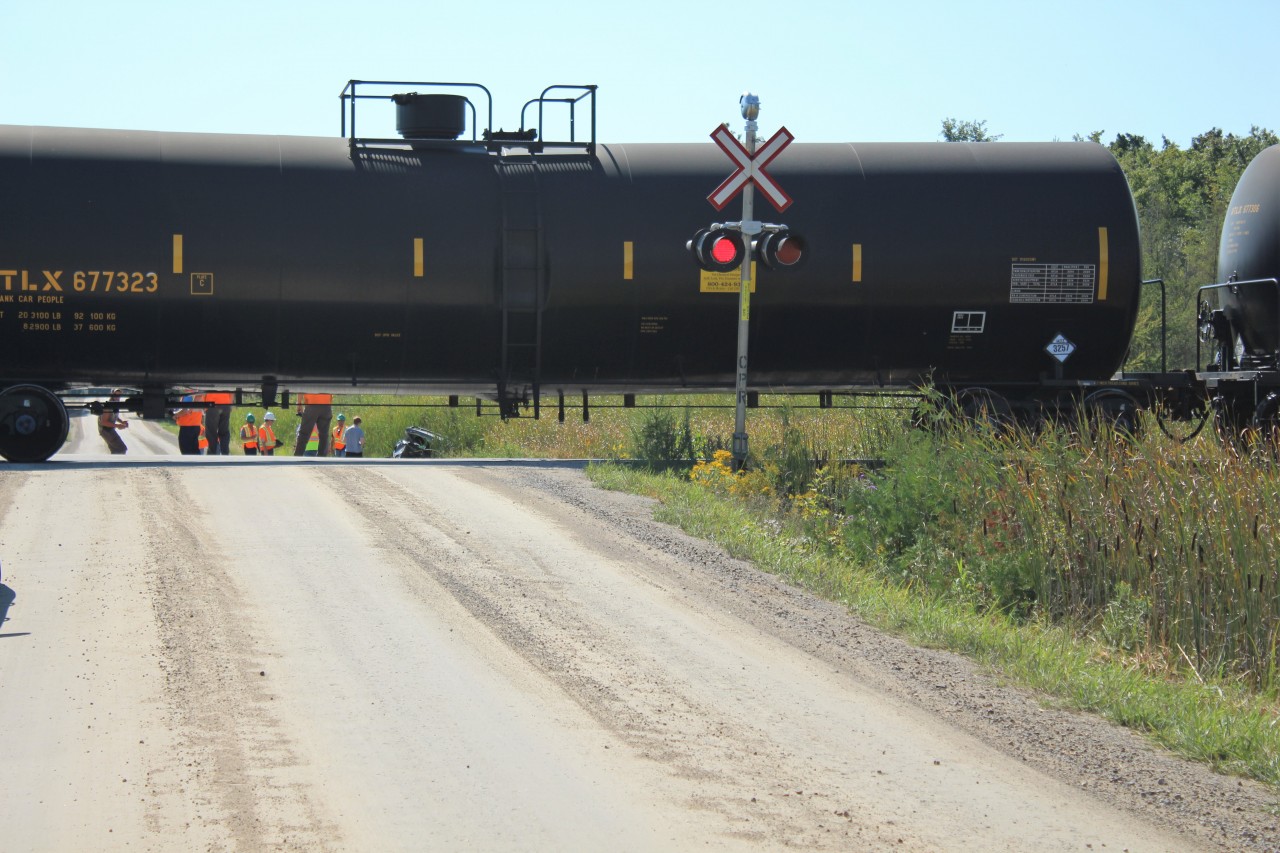 Just a few moments after CP 8565 clipped this SUV, CP workers and the engine personnel check out the damage. UTLX 677323 sits across concession #7 in Puslinch with the engines 3000+ feet up the tracks. The driver was Ok but was subsequently charged with driving under suspension and disobeying a railway crossing. This is one lucky lady to survive being hit by and ethanol and mixed tanker car train.