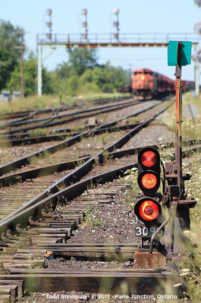 STOP!  Signal 309D shows an all red signal on the ex-Harrisburg Sub switch, now downgraded to a siding at Paris Junction on this very warm summer's day. In the distance (although blurred) is zebra striped CN 2420 and CN 2438 being used as teaching facilities for CN office staff. They were being taught coupling / uncoupling on the north main track. Beside is CN 4119 performing switiching duties on the north siding. When completed, it will head back with it's consist to the Brantford yard.