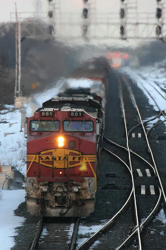 You had to be here for this one. It was a memorable experience.....a heads up via the internet...from what I remember it was a BNSF(Santa Fe)/NS/BNSF/CN conglomeration....as the last light was fading....I could see him dimming his headlight in the distance as an passenger train was lined up in the other direction...would I get doubled?...391 slowed to a crawl way back at Waterdown Road...I was thinking the daylight would disappear before he ever gets here and no shot....suddenly....I could see the heat and exhaust pouring out of the locomotives in the distance; and luckily he kept the ditch lights off; the telephoto effect did not do this one justice as he blasted by me..with that beautiful Santa Fe logo still on the front....

Does anyone know if this unit is now a CN 21xx ?