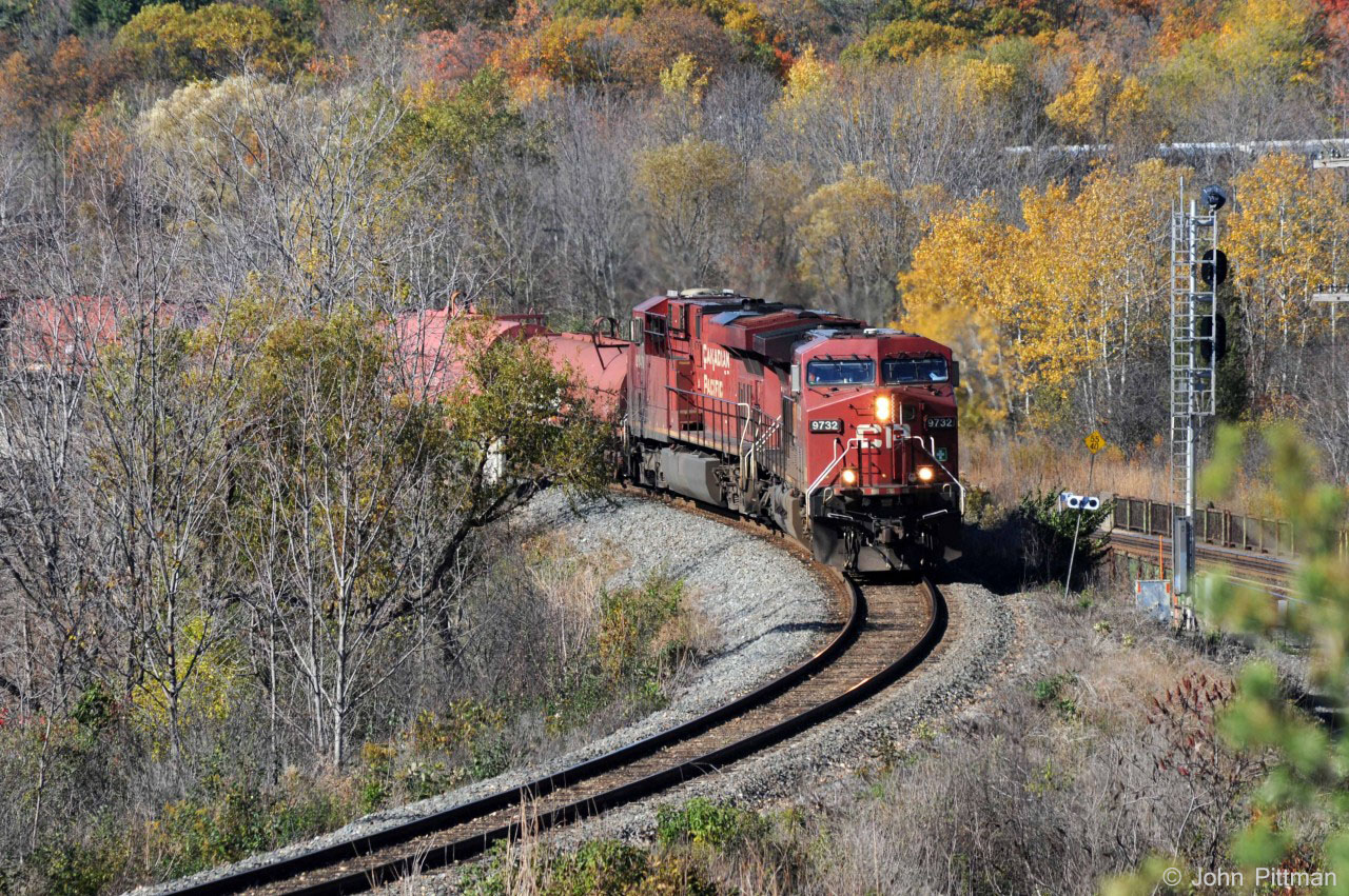 CP 9732 and 8849 lead their long heavy train at a safe speed downgrade on the Hamilton sub, as they approach the CTC section.  The first steel coil cars are on the bridge over Highway 403.  There is a big "S" curve here, with more of the train visible through the trees, above the CN Dundas Sub signal to the right.  
From observation and my scanner, it is apparent that operating trains this long and heavy on the Hamilton sub has some operational complications.  Speeds must be kept low to maintain control downhill, while helpers are needed to get some of the longest heaviest trains up to the top of the Niagara escarpment.   The requirement not to block grade crossings near Kinnear yard too long can be an issue.  
For CP trains, and the TH&B before, the preferred route between Hamilton and Toronto used to be over the CN Oakville sub, using the Canpa Connection in Etobicoke.  This route is significantly shorter and faster, and avoids ascending and descending the Niagara escarpment.  Presumably more GO train traffic and CN usage charges and restrictions have seriously discouraged the routing of CP trains via the CN Oakville sub in the years since the TH&B's long term arrangement expired.