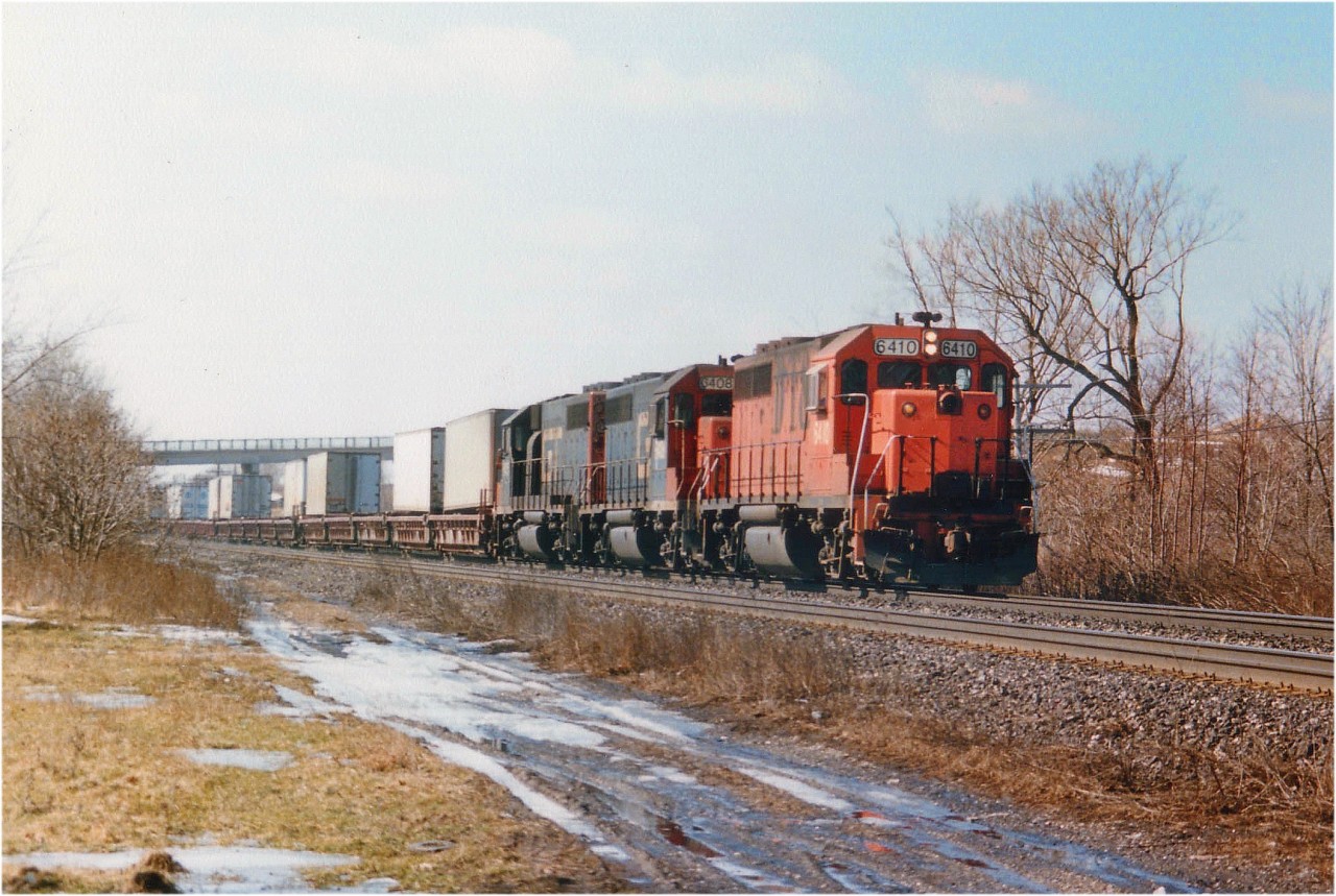 For a brief spell in the late 1980's GTW, which was now part of the CN empire; ran what was dubbed "The Laser", a daily TOFC (trailer on flat car) train; I believe Detroit to Toronto/Montreal, and I am not even sure of the train number: I recall 231/232 but would appreciate corrections.  The GT had taken over the DT&I (Detroit, Toledo & Ironton) back in 1983 and their power was intregrated into GTW, so it was possible to see one of their original paint units in service on the Laser. Here, we catch one on the lead as it rolls east thru Aldershot past the old Howard Rd extension that was a popular place for train nuts to hang out at that time. With a third rail going in a few years ago, this location became redundant and now is just a memory. Power is DT&I 6410, GT6408 and 6415. Note the DT&I has been renumbered into the GTW roster.  That is Lemonville Rd bridge in the background.