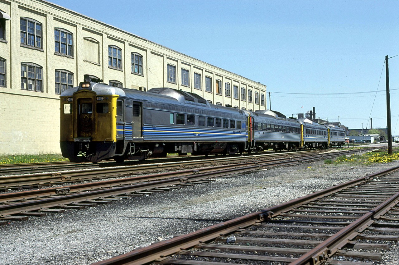 VIA #85 has just completed a stop at Kitchener and is now heading to Stratford, St Marys and London.
I finally got a sunny day in March of 1980.
The building in the background was the Boehmer Box Factory. From what I have just read, it looks like the factory relocated, and this building is being re-purposed. The buildings further back were once furniture factories.