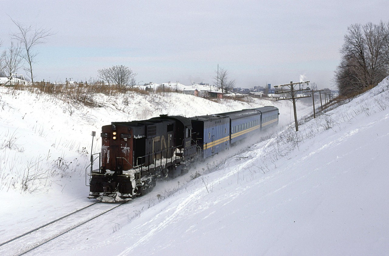 VIA 85 is kicking up the snow as it leaves the urban area of Kitchener. This is now a tree-lined ROW with sprawl reaching well beyond this point.