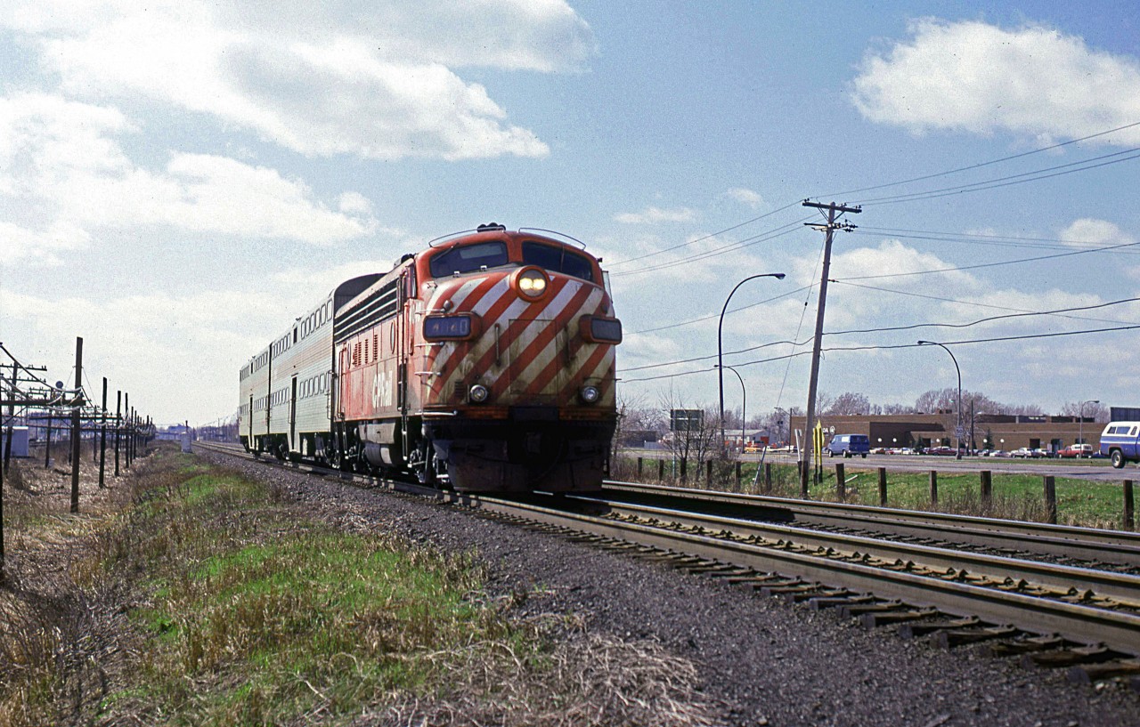 After finishing up my work term in northern Quebec, I flew to my parent's place in Halifax. On a layover at Dorval, I stored my bags and went trackside for a short time. 
An eastbound (inbound) commuter train, running on the CPR zips past the Dorval platform, visible at the rear of the train.