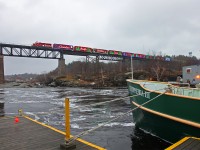The 2014 CP Holiday Train slows while crossing the trestle in Parry Sound to allow photographers a decent chance at a shot in the overcast late afternoon light. The MV Chippewa III tugs against its mooring lines in the waters of the Seguin River below, which are still angry from the run-off of about 4 feet of snow that had melted over the past few days. This vessel was built in the mid-50s to serve as a "Maid of the Mist" ship in much angrier waters at the foot of Niagara Falls.