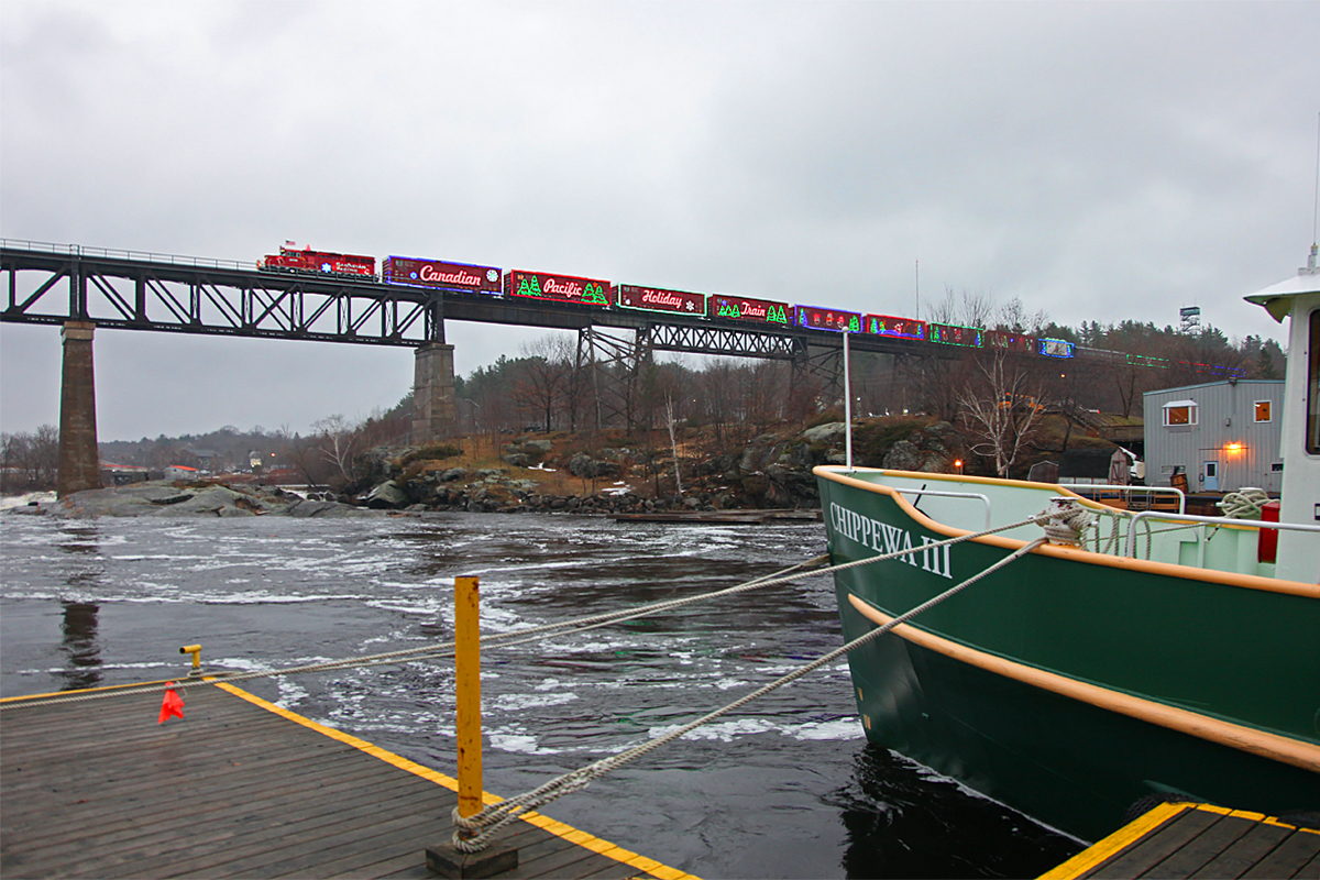 The 2014 CP Holiday Train slows while crossing the trestle in Parry Sound to allow photographers a decent chance at a shot in the overcast late afternoon light. The MV Chippewa III tugs against its mooring lines in the waters of the Seguin River below, which are still angry from the run-off of about 4 feet of snow that had melted over the past few days. This vessel was built in the mid-50s to serve as a "Maid of the Mist" ship in much angrier waters at the foot of Niagara Falls.